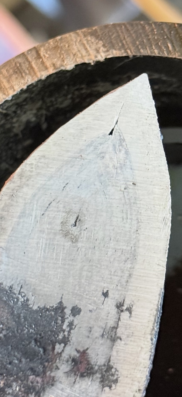 Close-up of an open weld seam near the pointed end of the steel blade