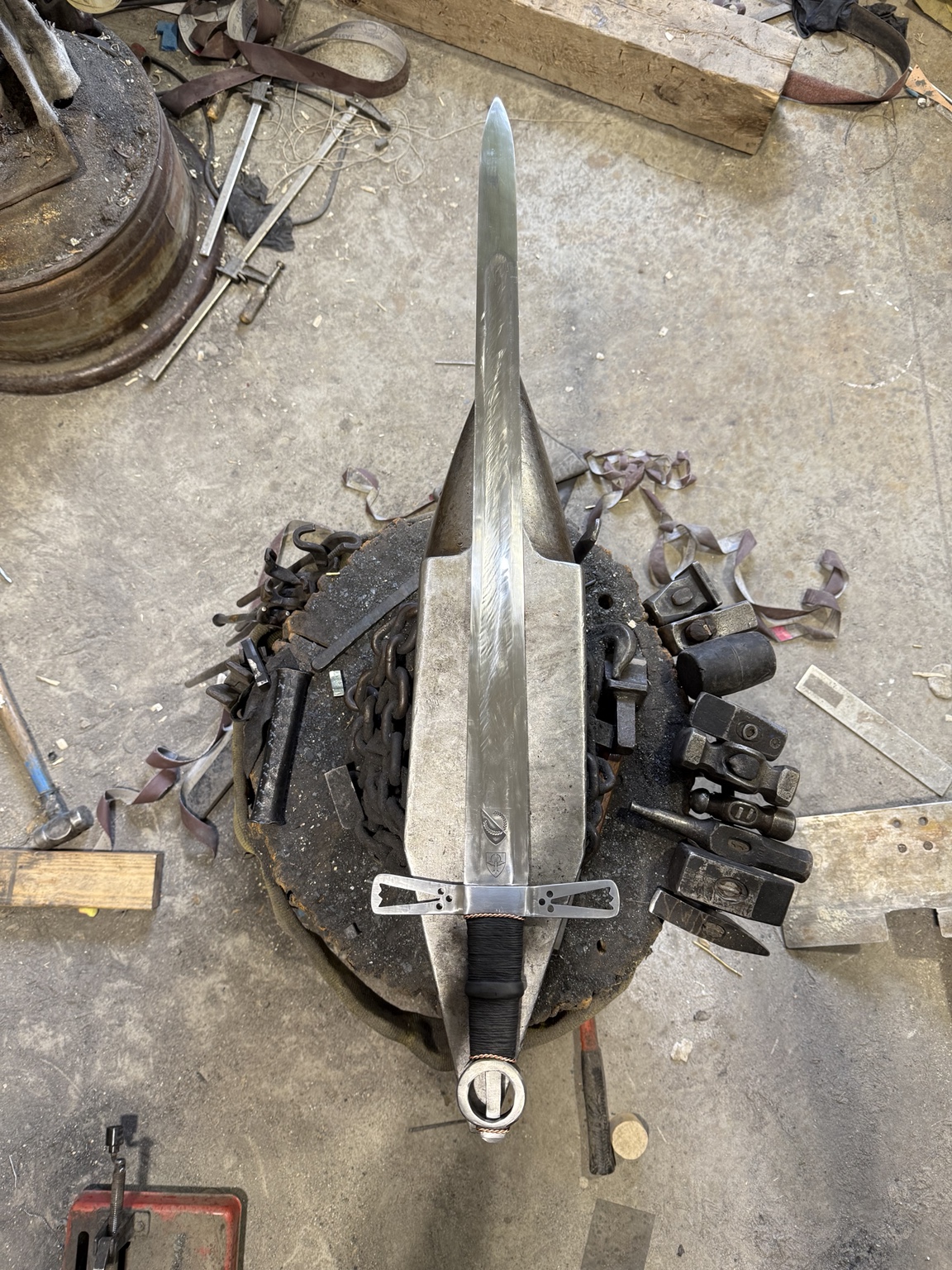 Completed Loch Salann Sword of State with ring pommel laid out vertically on an anvil