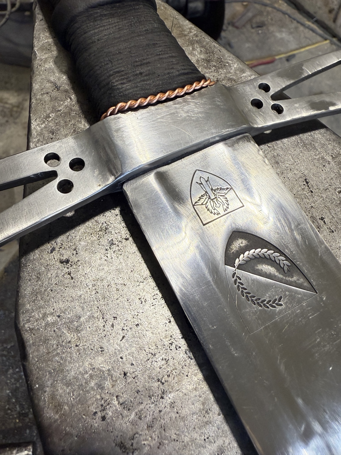 Close-up of pierced ermine spots in the guard and heraldic engraving near the sword shoulder