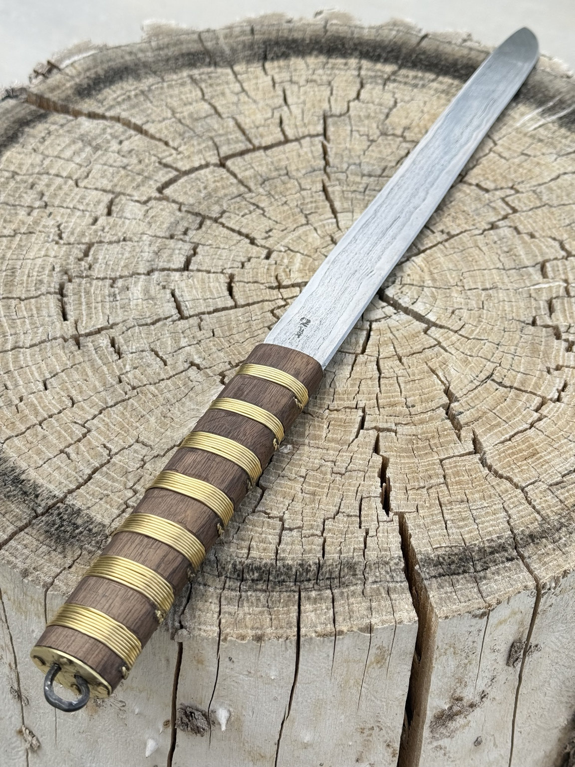 Completed Scandinavian long knife displayed diagonally on a stump
