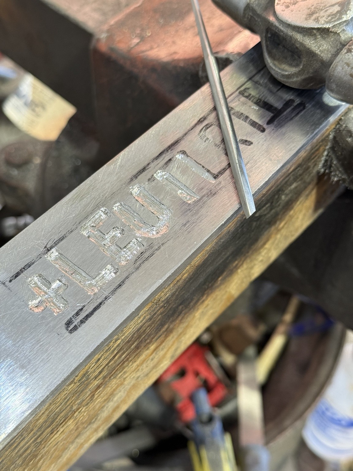 Close angled view of inlaid letters and marked lines on the River Witham-inspired sword before final blade finishing